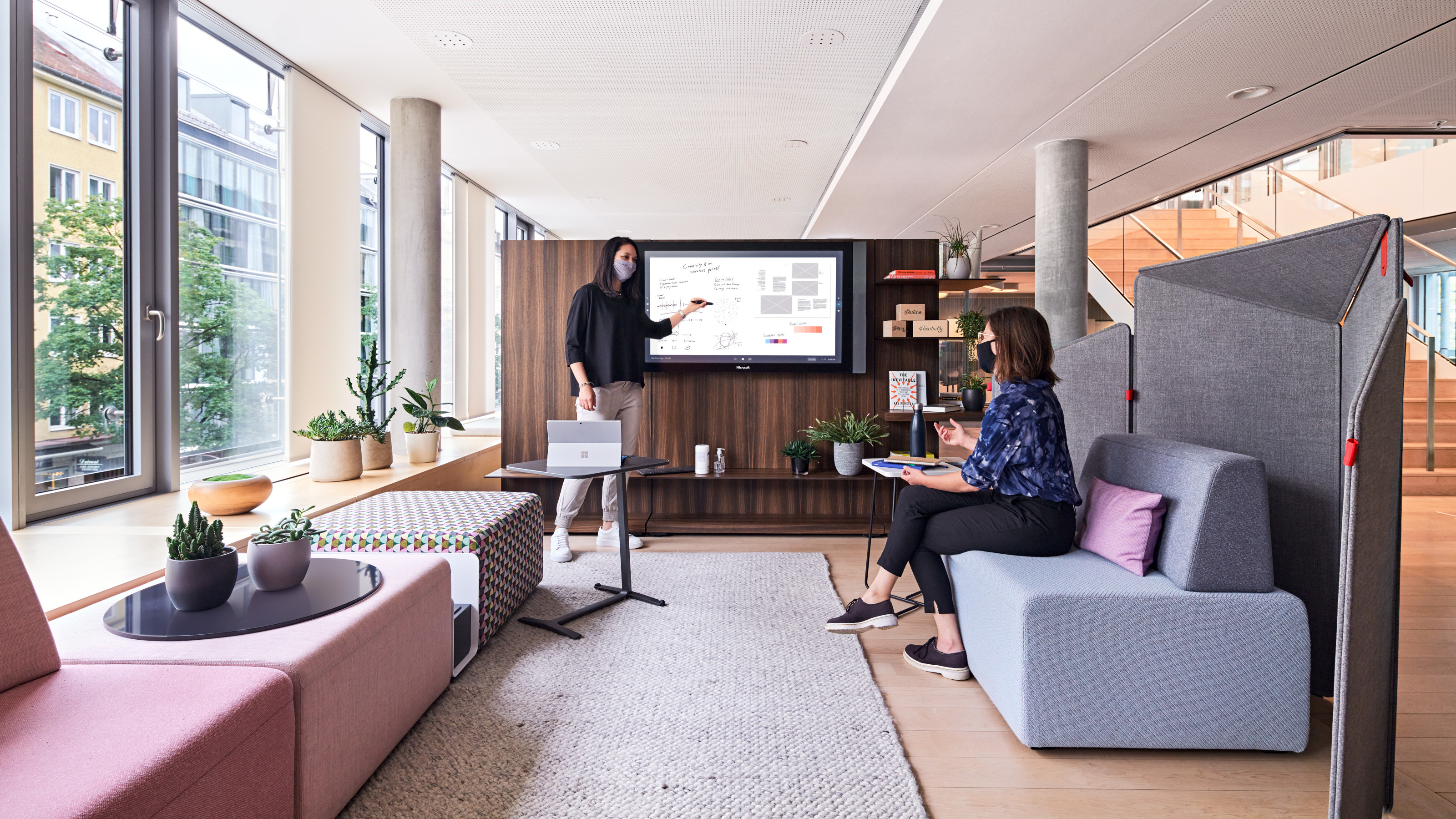 pic of 2 women in office lounge setting wearing masks