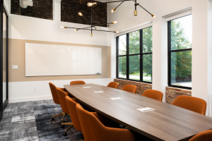 HQ on Main teleconference room with with orange swivel chairs and wood table with integrated technology and modern ceiling pendant lighting