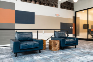 HQ on Main lounge area with blue chairs and round wood table blue Milliken modular carpet